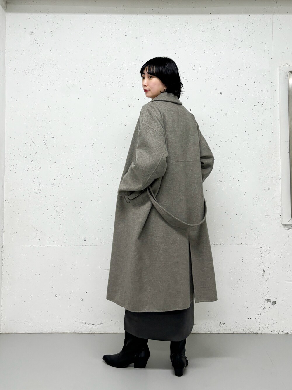 グレー系のステンカラーコート、ピンク系のシャツ/ブラウス、グレー系のスカートを着用したレディースの冬コーディネートの2枚目の写真