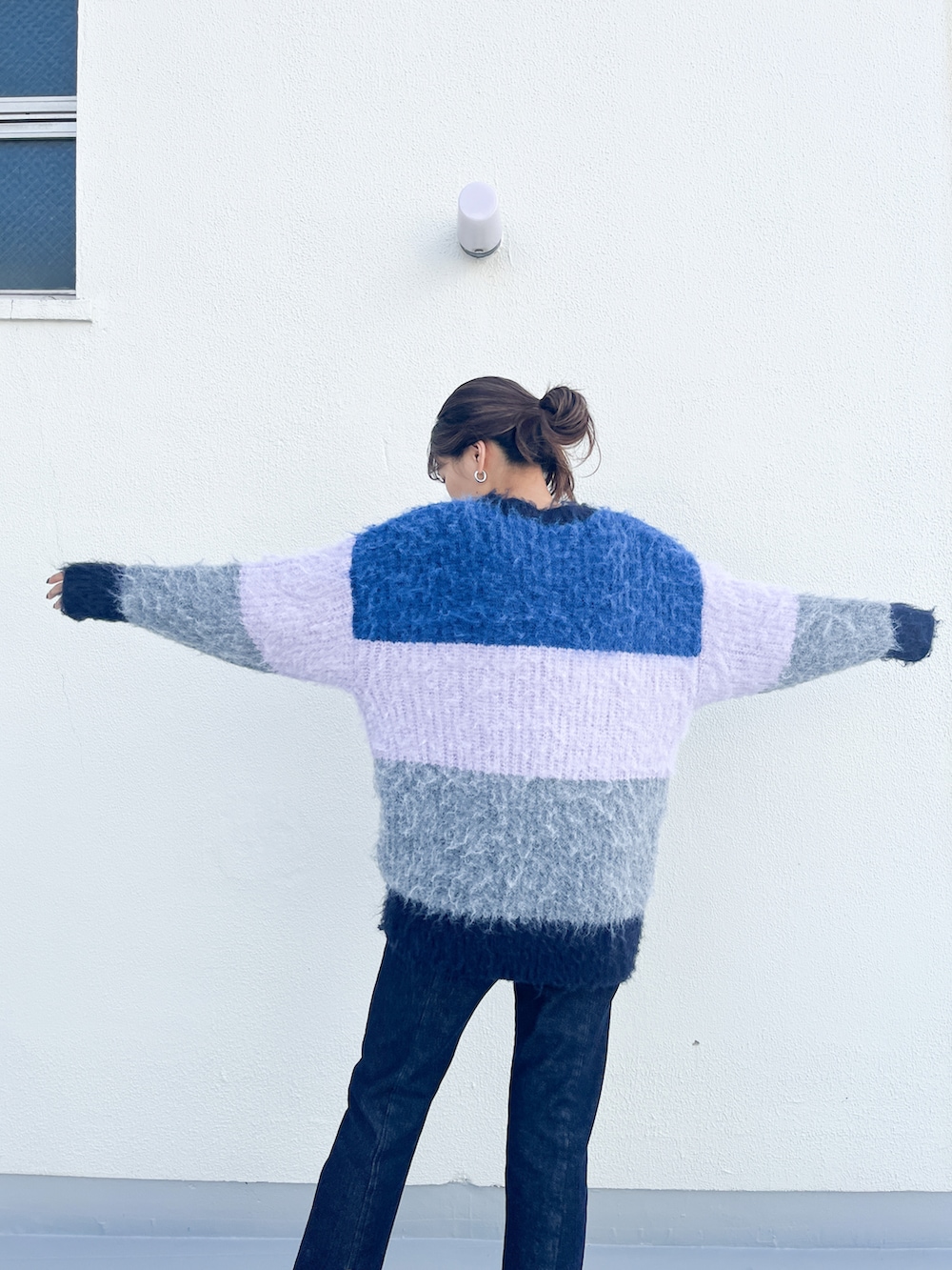 ピンク系のニット/セーター、ブルー系のデニムパンツ、ブラック系のブーツを着用したレディースの秋コーディネートの4枚目の写真