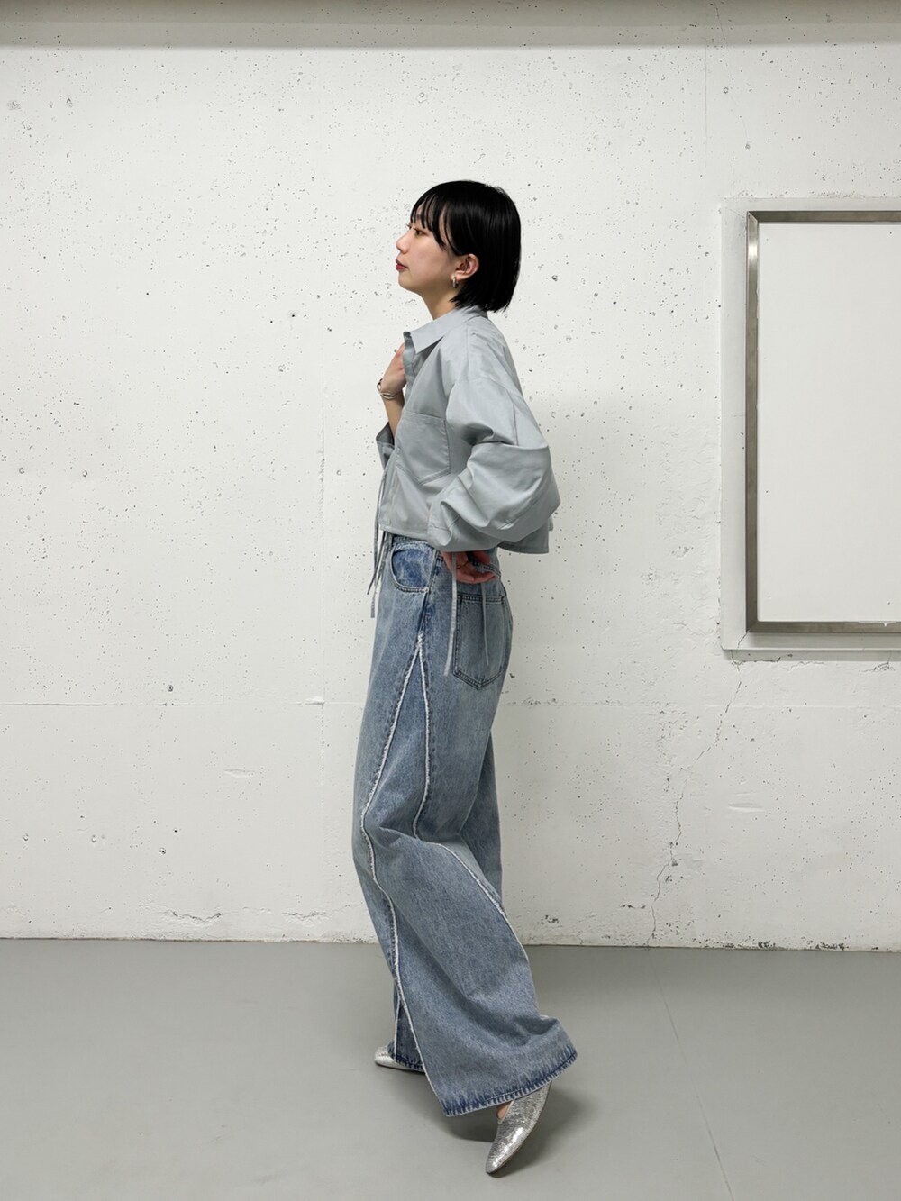 ベージュ系のステンカラーコート、グリーン系のシャツ/ブラウス、ブルー系のデニムパンツを着用したレディースの春コーディネートの4枚目の写真