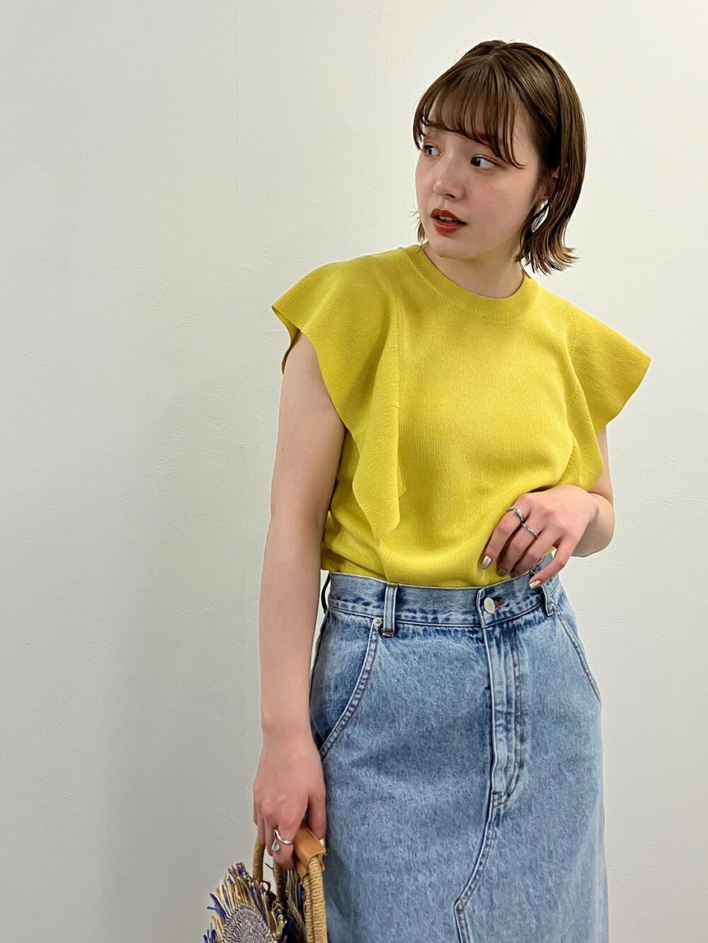 イエロー系のニット/セーター、ブルー系のスカート、ホワイト系のサンダルを着用したレディースの春コーディネートの3枚目の写真