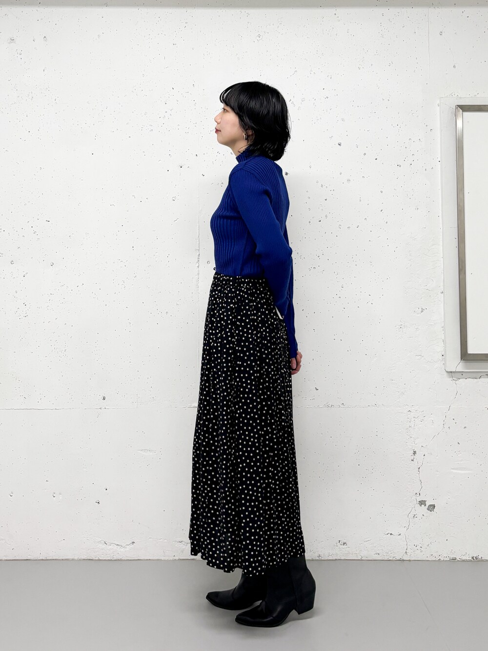 ブラック系のスカート、ブルー系のニット/セーター、ブラック系のブーツを着用したレディースの冬コーディネートの2枚目の写真