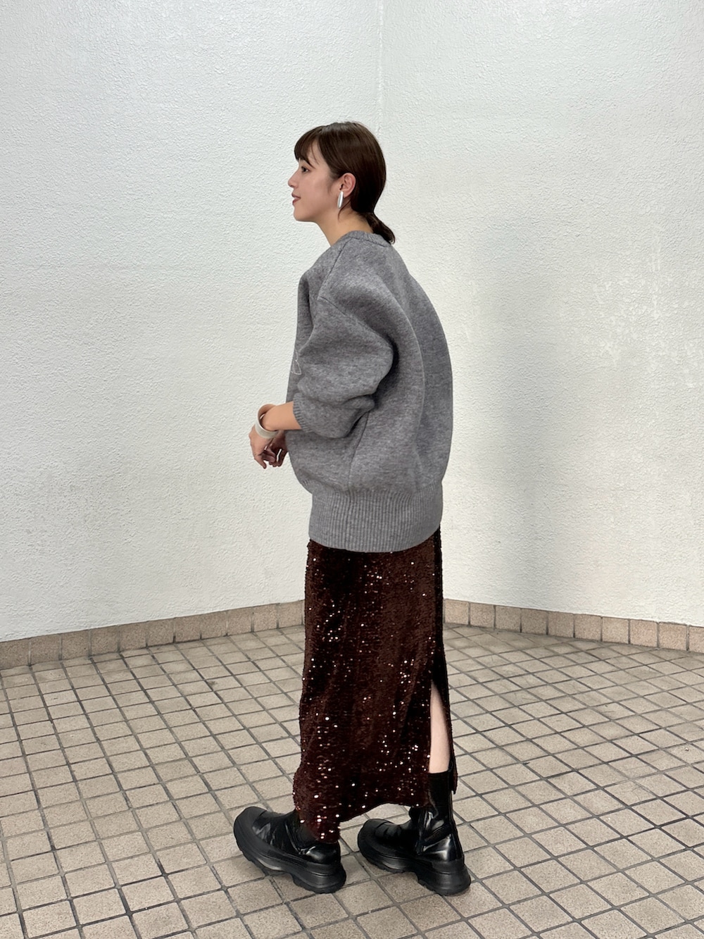 グレー系のニット/セーター、ブラウン系のスカート、ブラック系のブーツを着用したレディースの秋コーディネートの4枚目の写真