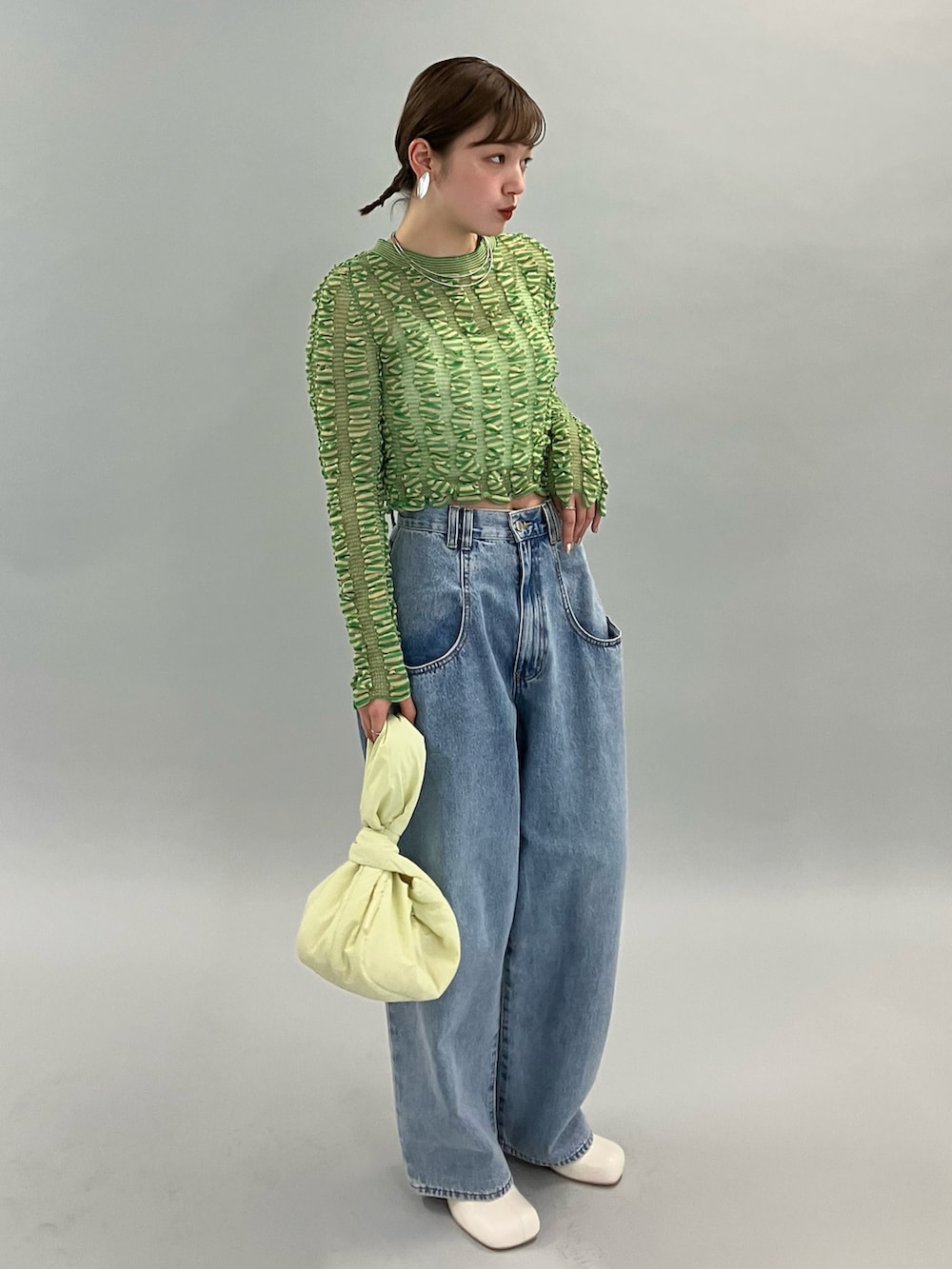 ブルー系のデニムパンツ、ホワイト系のブーツ、グリーン系のニット/セーターを着用したレディースの夏コーディネートの4枚目の写真