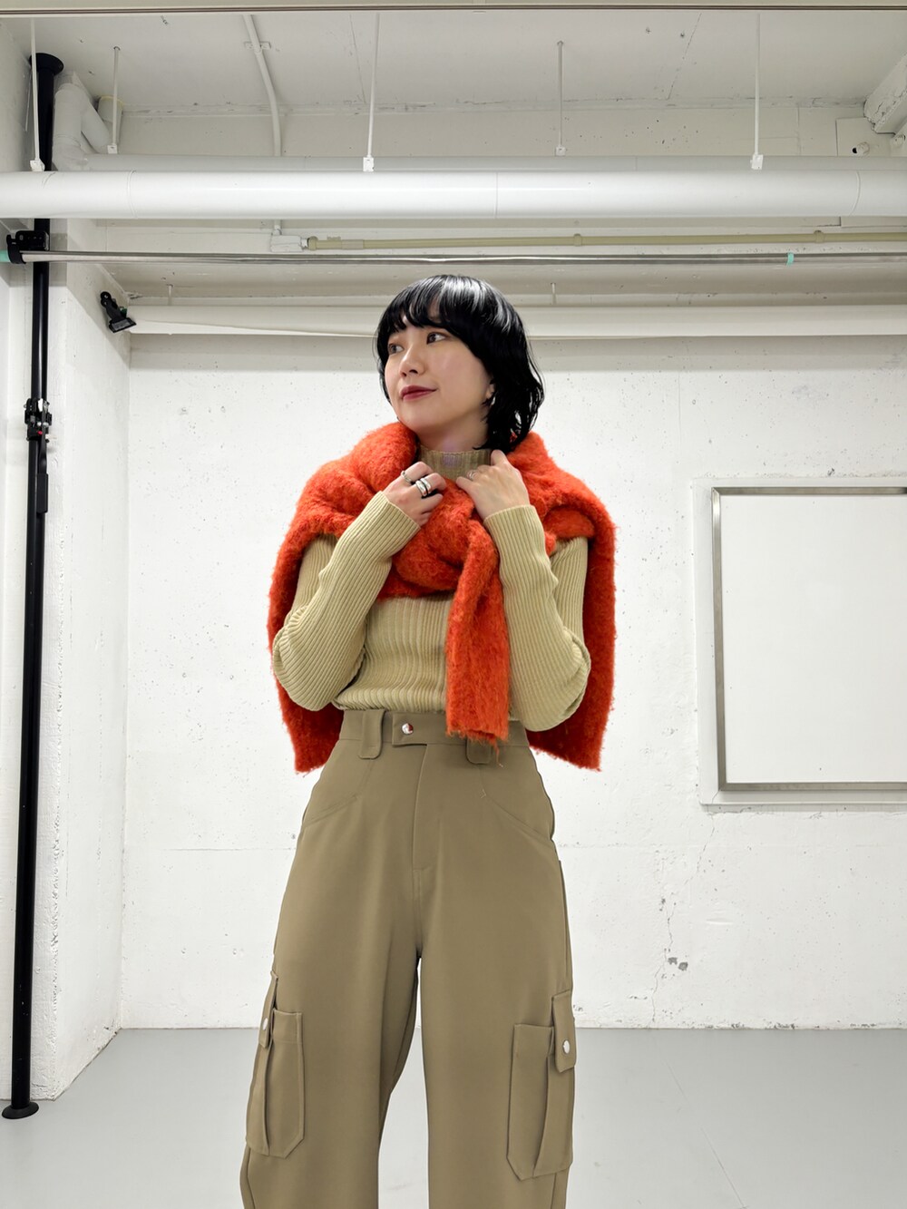 ベージュ系のニット/セーター、グリーン系のその他パンツ、オレンジ系のカーディガン/ボレロを着用したレディースの冬コーディネートの2枚目の写真