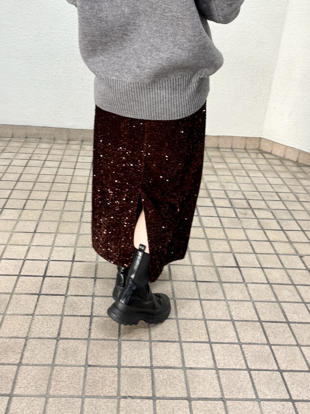 グレー系のニット/セーター、ブラウン系のスカート、ブラック系のブーツを着用したレディースの秋コーディネートの3枚目の写真