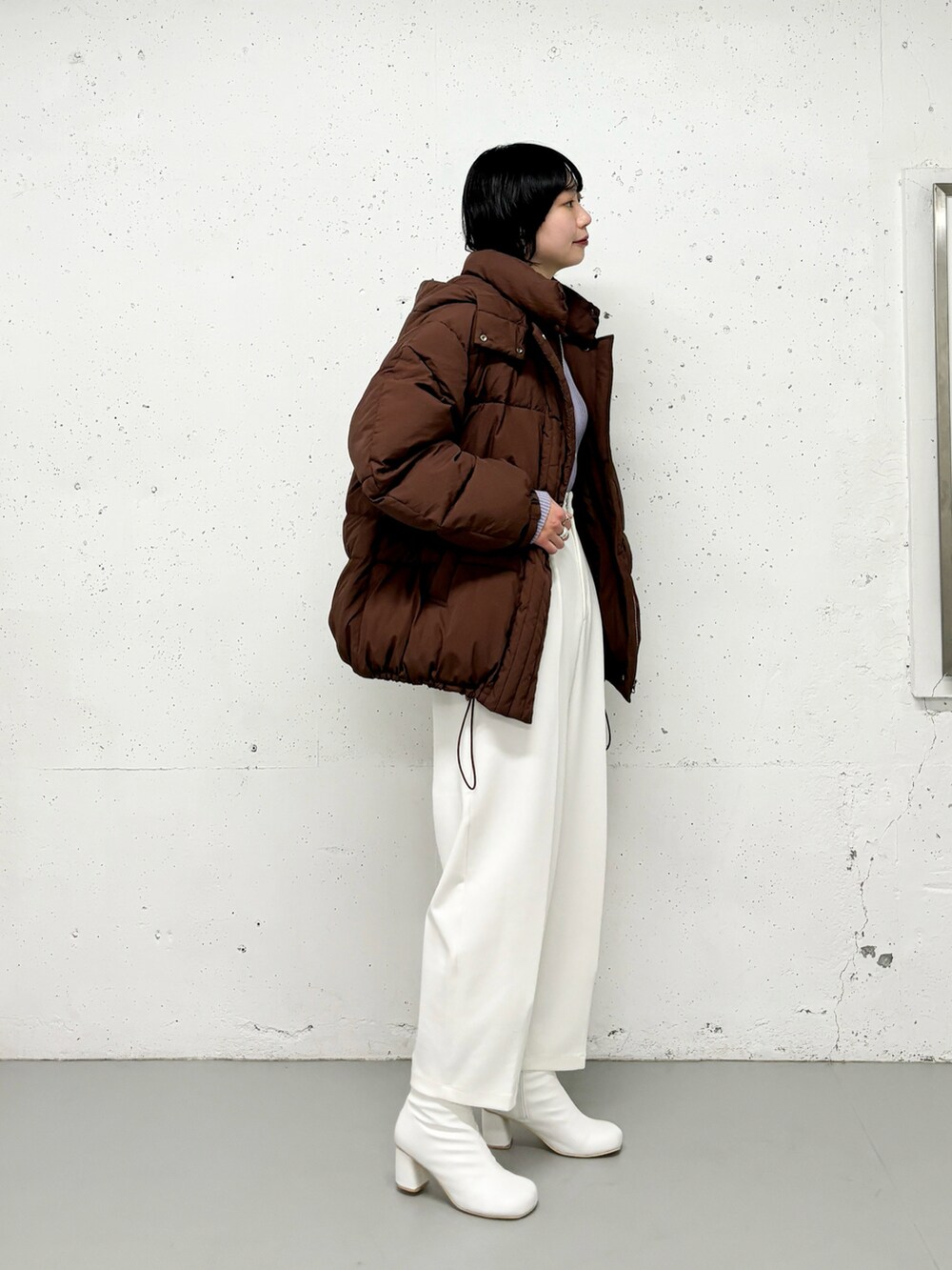 ブラウン系のダウンジャケット/コート、パープル系のニット/セーター、ホワイト系のその他パンツを着用したレディースの冬コーディネートの2枚目の写真