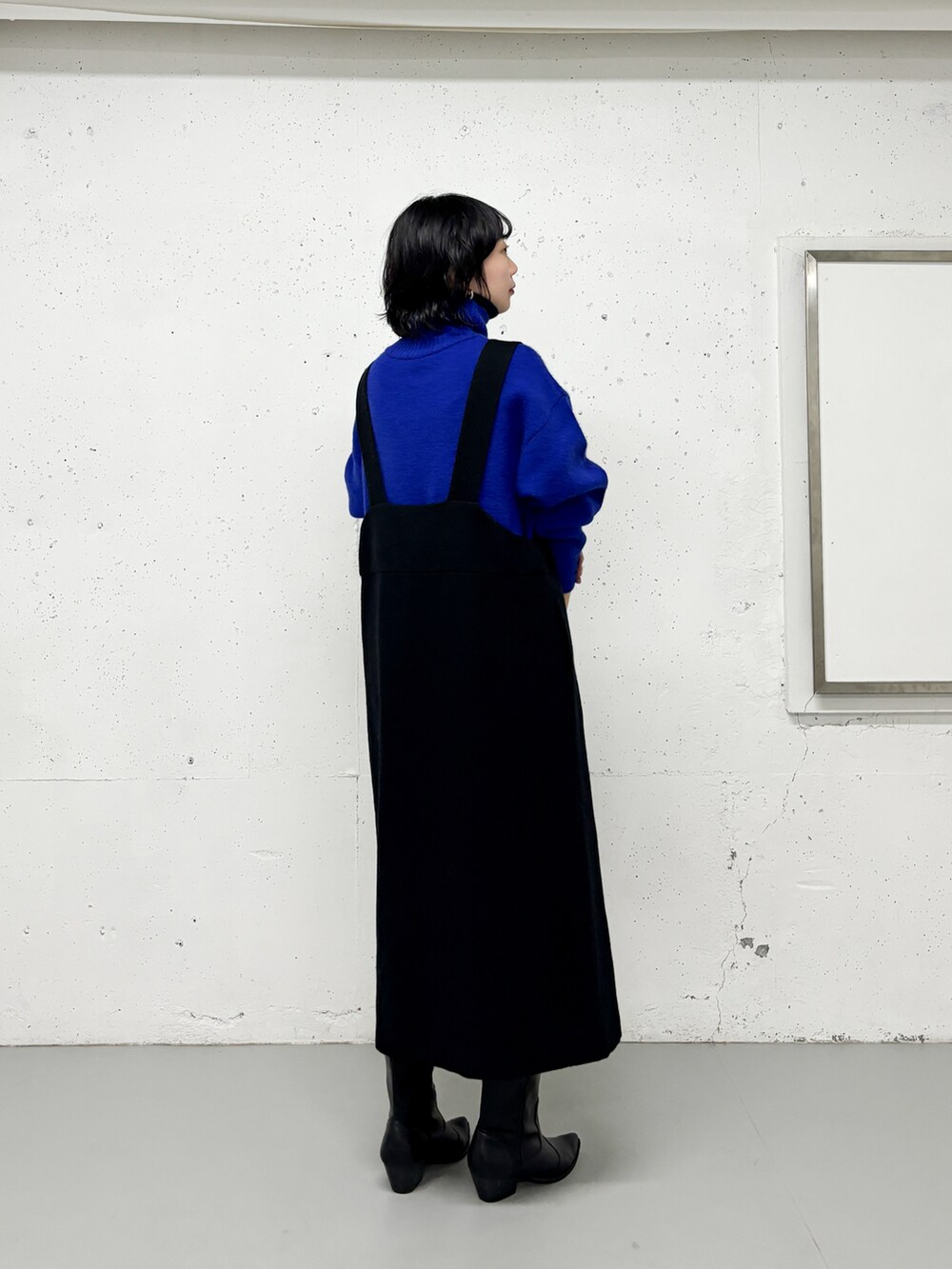 ブラック系のワンピース、ブルー系のニット/セーター、ブラック系のブーツを着用したレディースの冬コーディネートの2枚目の写真