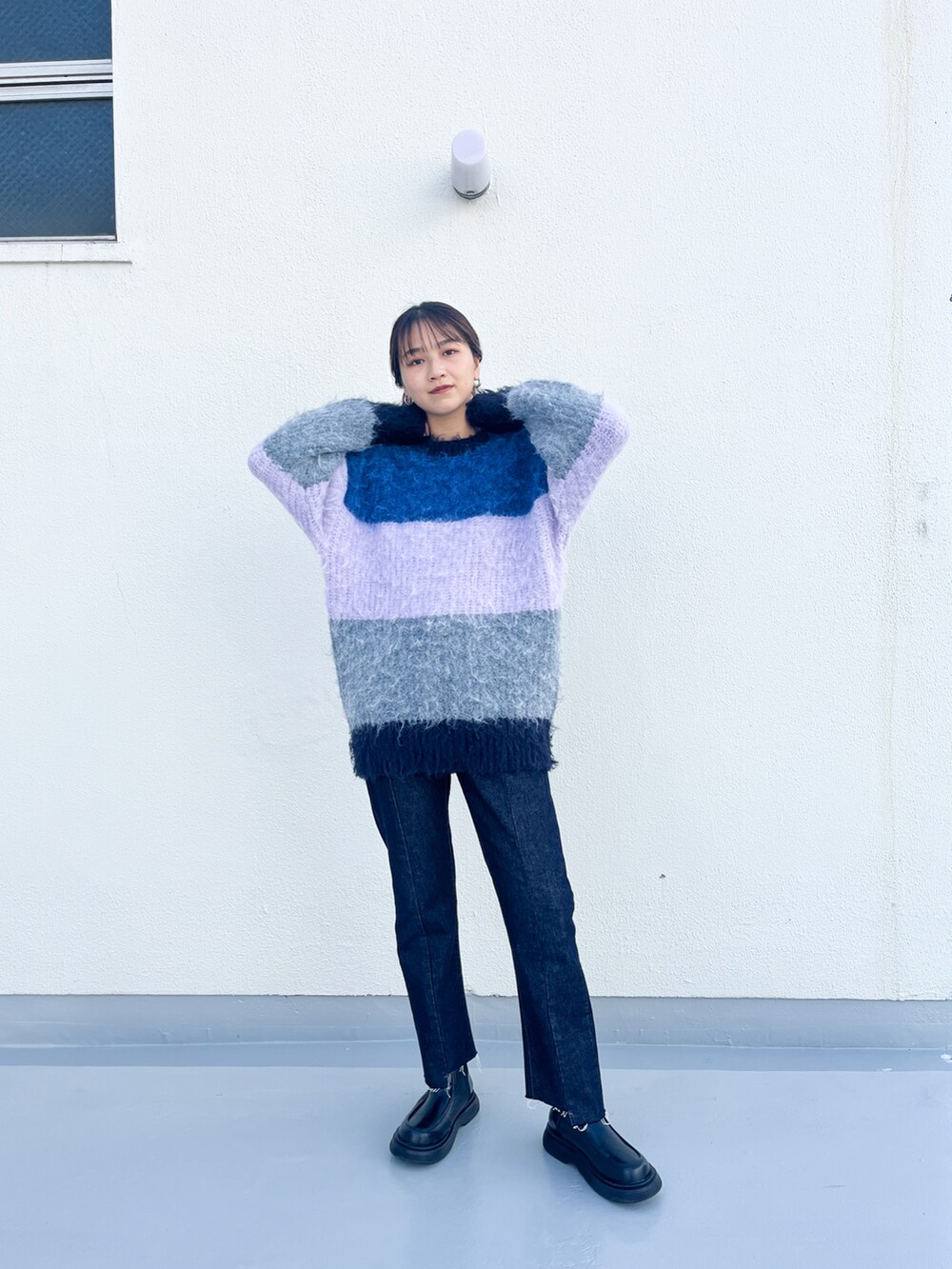 ピンク系のニット/セーター、ブルー系のデニムパンツ、ブラック系のブーツを着用したレディースの秋コーディネートの2枚目の写真