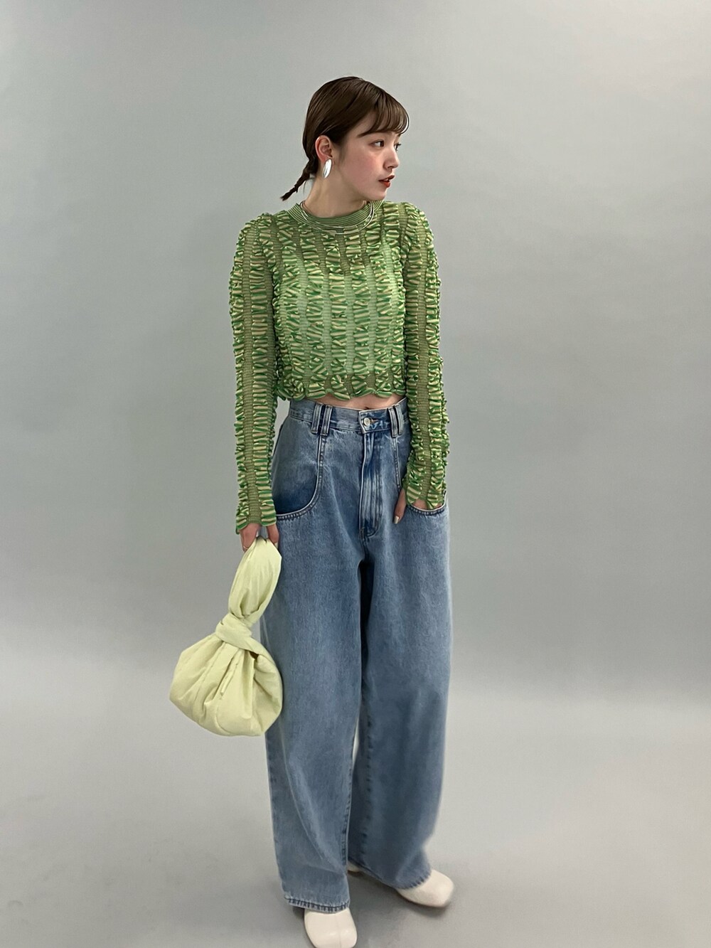 ブルー系のデニムパンツ、ホワイト系のブーツ、グリーン系のニット/セーターを着用したレディースの夏コーディネートの3枚目の写真