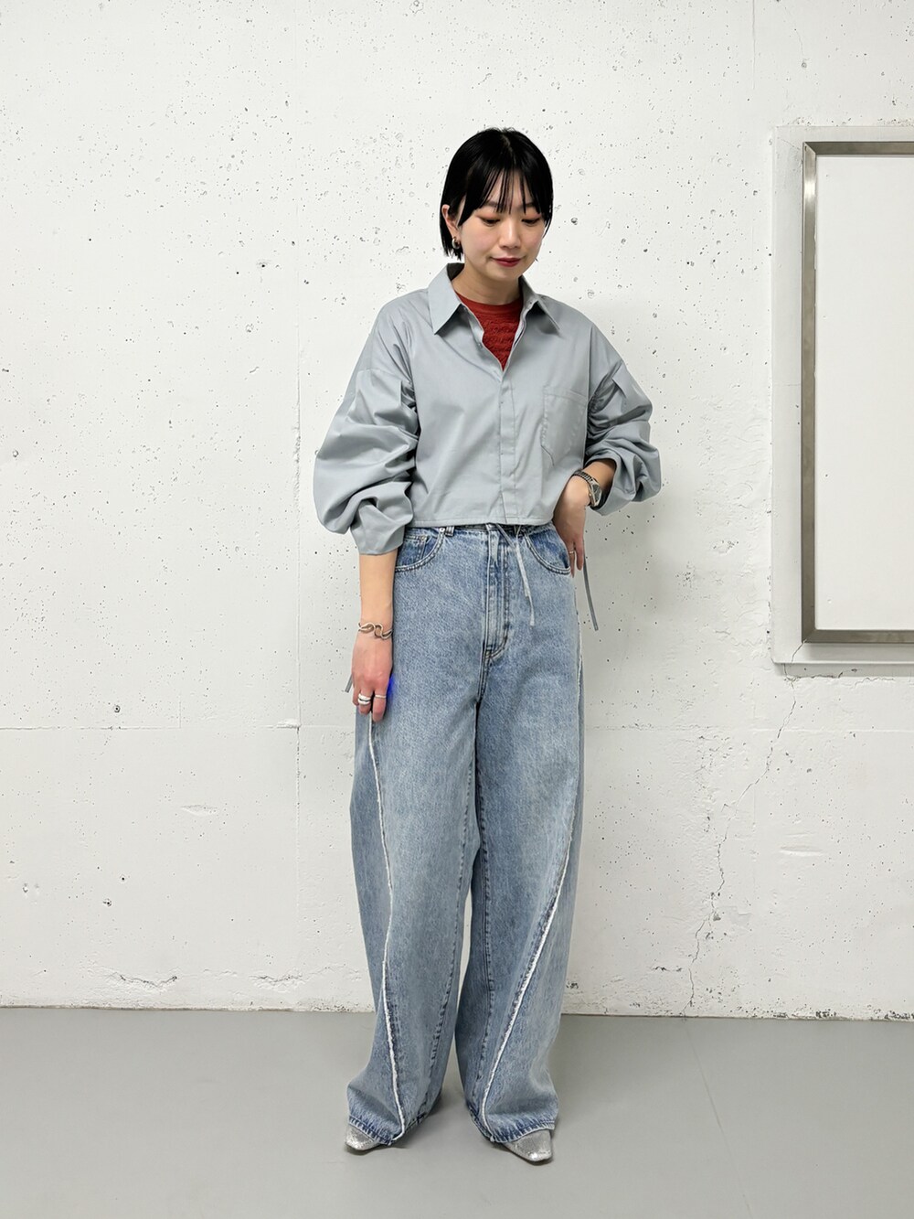 ベージュ系のステンカラーコート、グリーン系のシャツ/ブラウス、ブルー系のデニムパンツを着用したレディースの春コーディネートの3枚目の写真