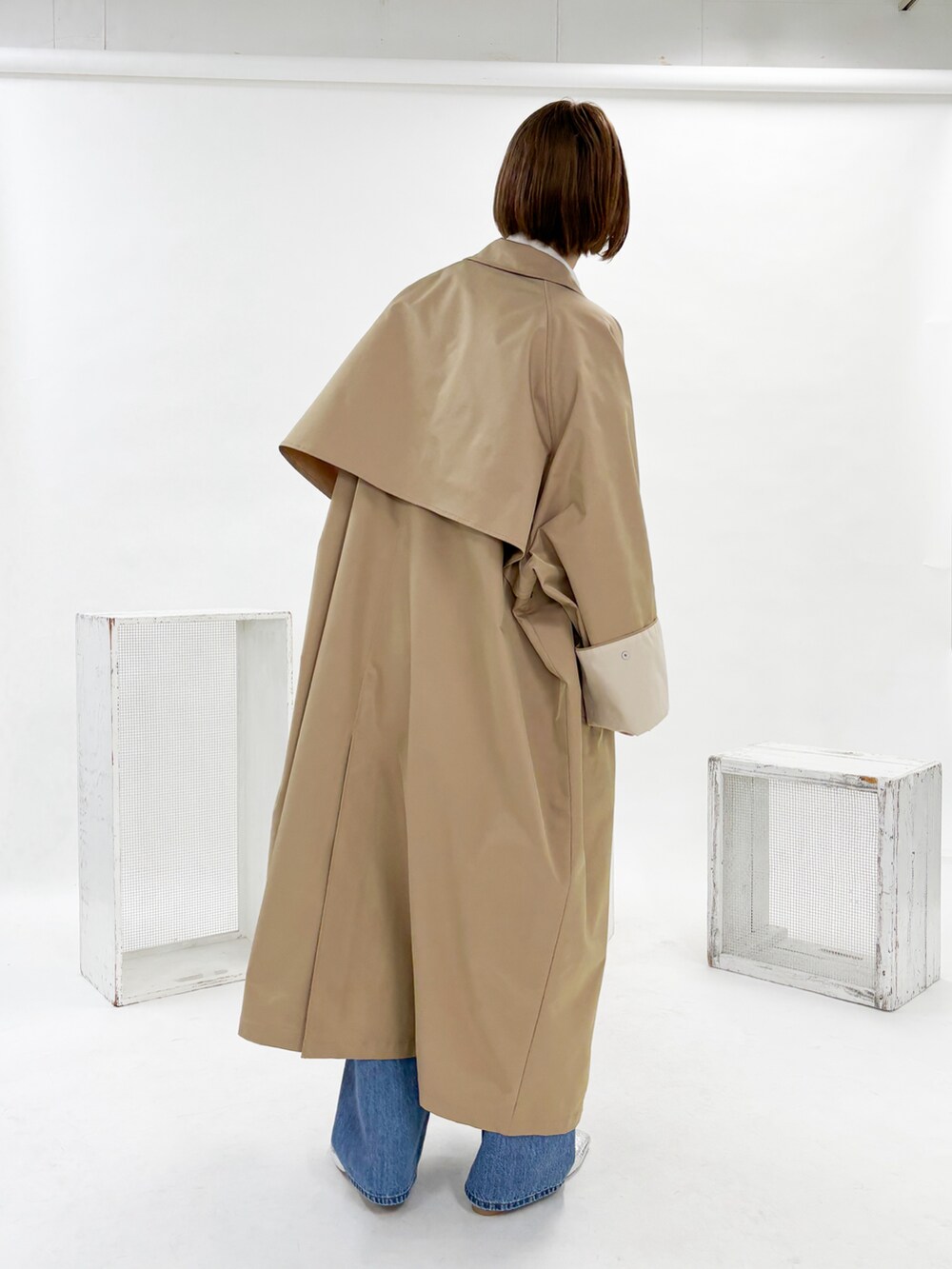 ベージュ系のステンカラーコート、ホワイト系のシャツ/ブラウス、ブルー系のデニムパンツを着用したレディースの冬コーディネートの2枚目の写真