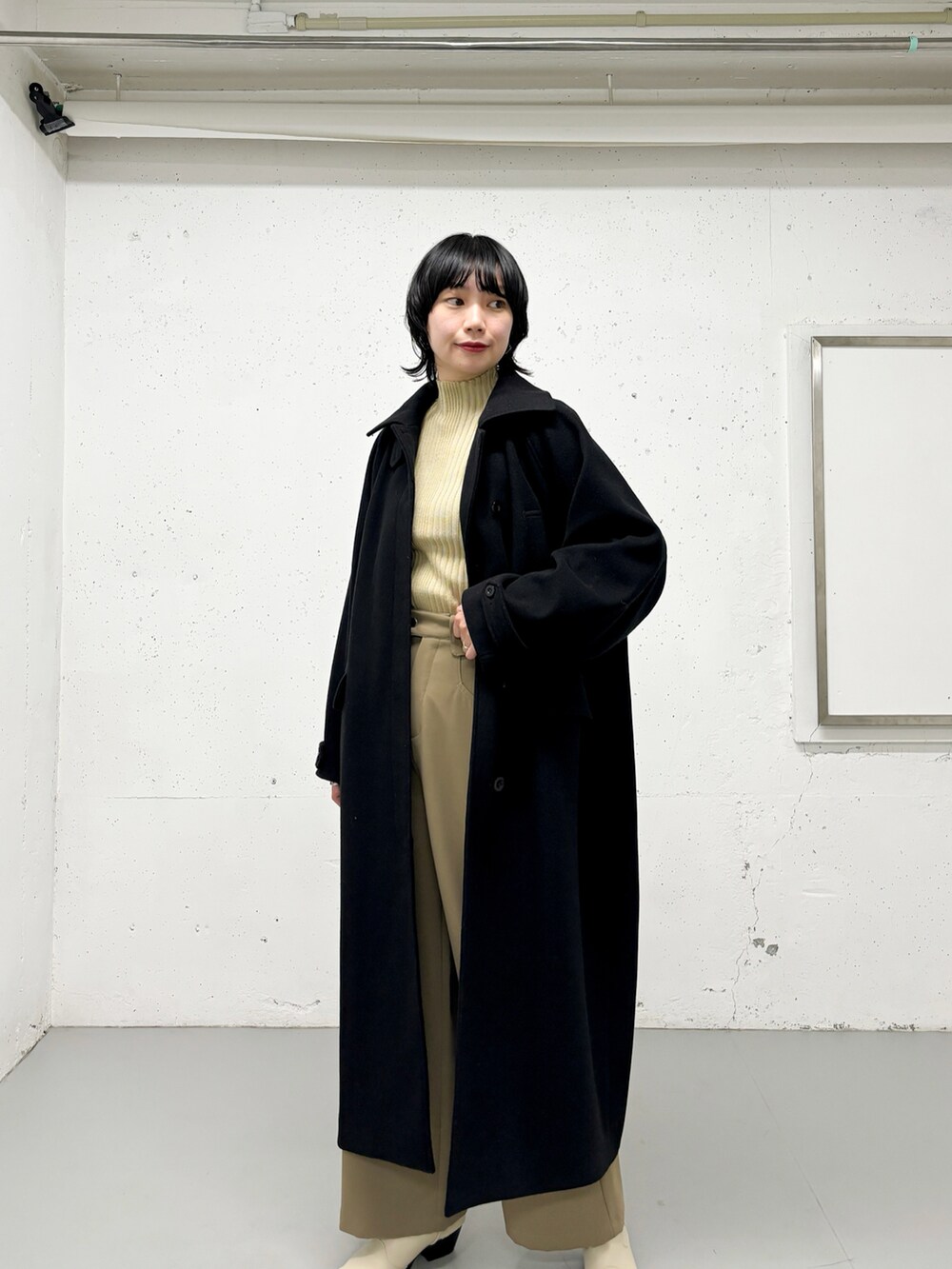 ブラック系のステンカラーコート、ベージュ系のニット/セーター、グリーン系のその他パンツを着用したレディースの冬コーディネートの4枚目の写真