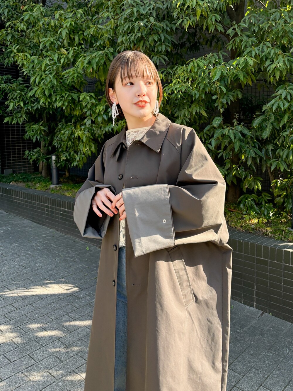 ブルー系のデニムパンツ、グレー系のステンカラーコートを着用したレディースの冬コーディネートの2枚目の写真