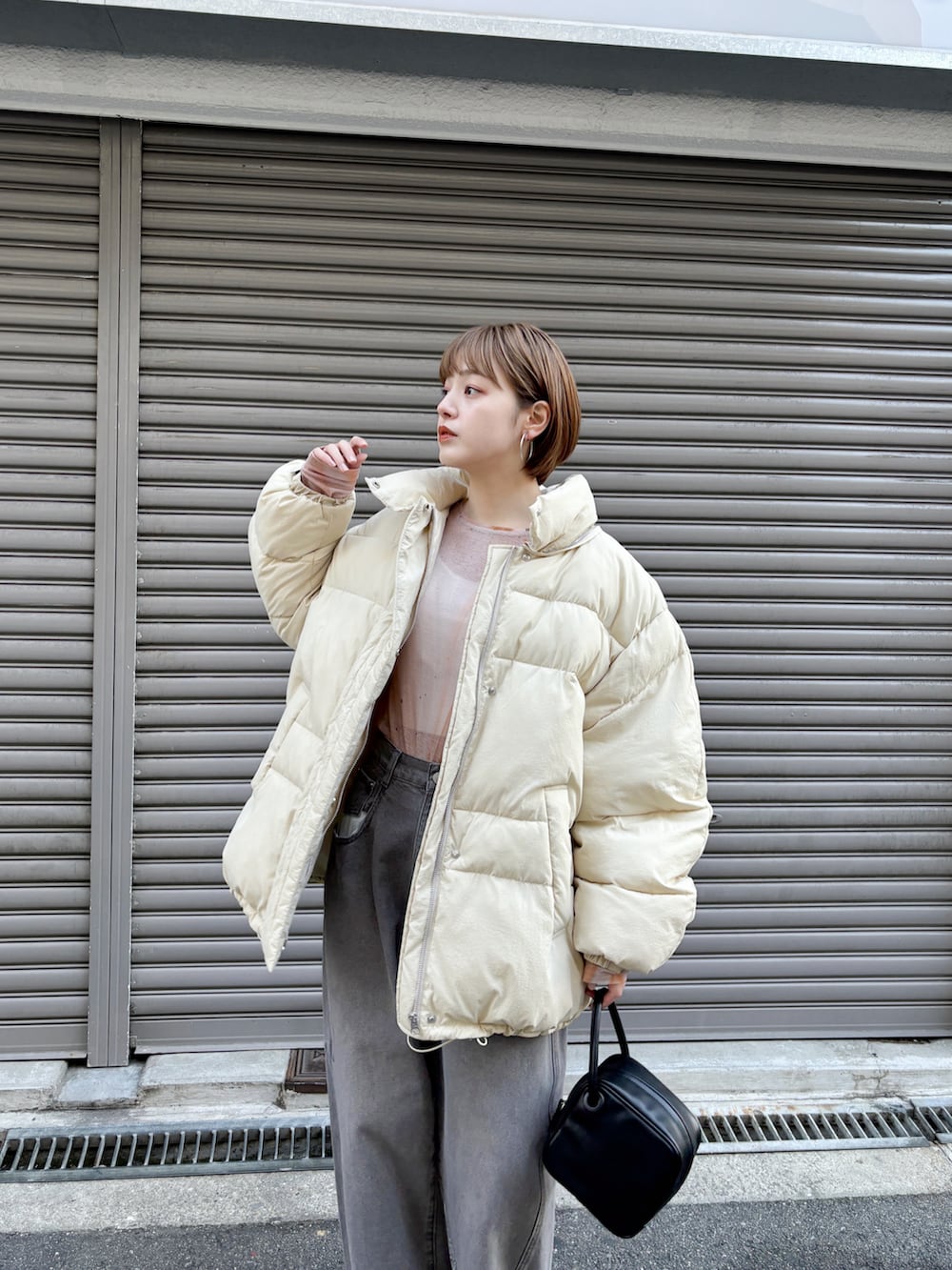 ベージュ系のダウンジャケット/コート、ブラック系のハンドバッグ、グレー系のデニムパンツを着用したレディースの冬コーディネートの2枚目の写真