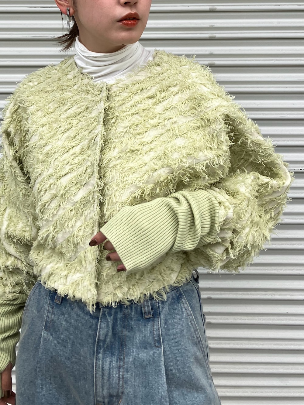 ブルー系のデニムパンツ、ホワイト系のブーツ、グリーン系のカーディガン/ボレロを着用したレディースの秋コーディネートの2枚目の写真