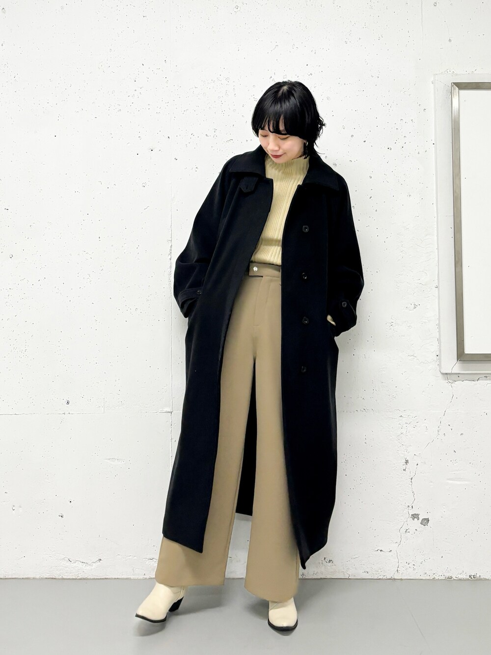 ブラック系のステンカラーコート、ベージュ系のニット/セーター、グリーン系のその他パンツを着用したレディースの冬コーディネートの3枚目の写真