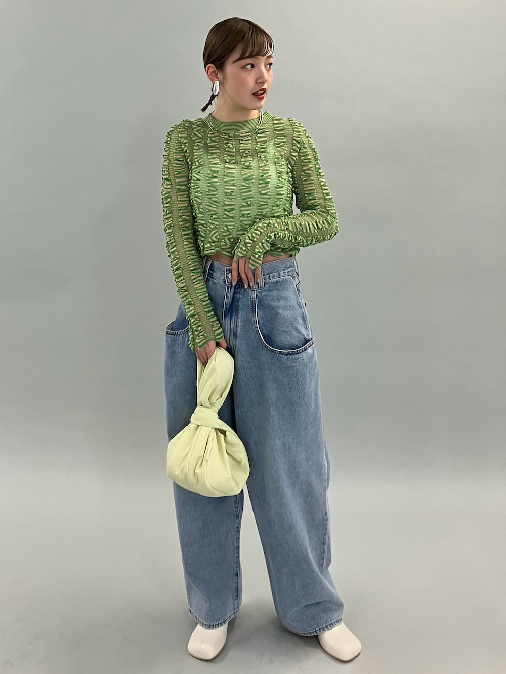 ブルー系のデニムパンツ、ホワイト系のブーツ、グリーン系のニット/セーターを着用したレディースの夏コーディネートの2枚目の写真