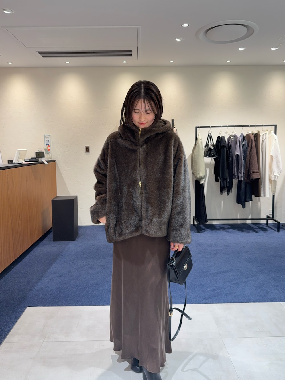 ホワイト系のニット/セーター、ブラウン系のブルゾン、ブラウン系のスカートを着用したレディースの冬コーディネートの2枚目の写真