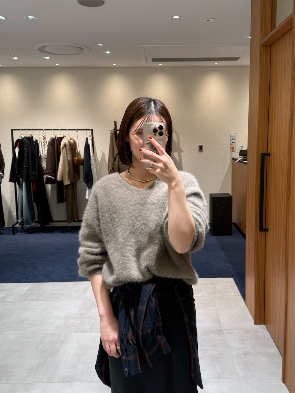 ブラウン系のニット/セーター、ブラック系のスカート、ブルー系のシャツ/ブラウスを着用したレディースの冬コーディネートの2枚目の写真