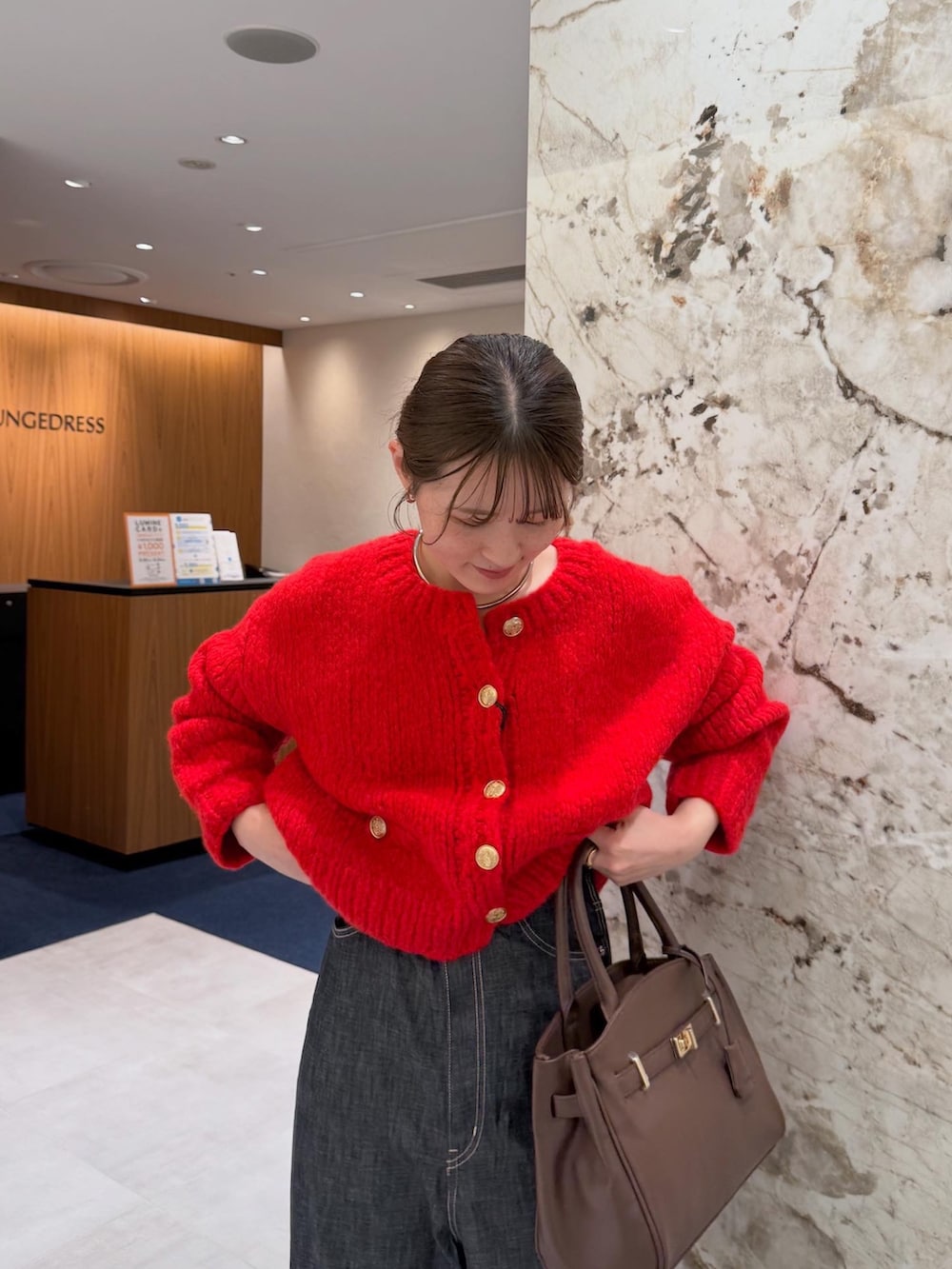 レッド系のニット/セーター、ブルー系のデニムパンツ、ブラウン系のブーツを着用したレディースの秋コーディネートの4枚目の写真