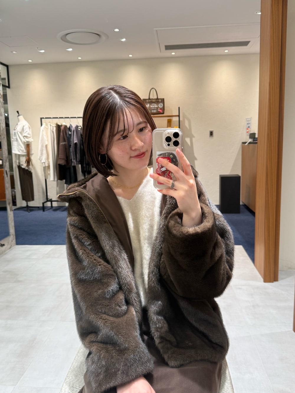 ホワイト系のニット/セーター、ブラウン系のブルゾン、ブラウン系のスカートを着用したレディースの冬コーディネートの4枚目の写真