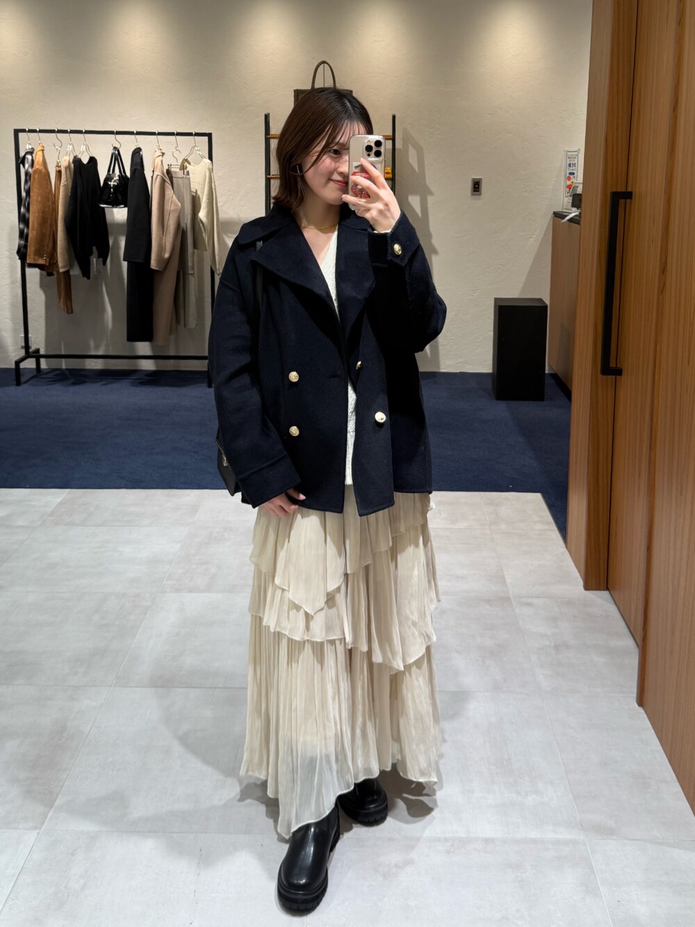 ホワイト系のニット/セーター、ホワイト系のスカート、ブラック系のブーツを着用したレディースの冬コーディネートの3枚目の写真