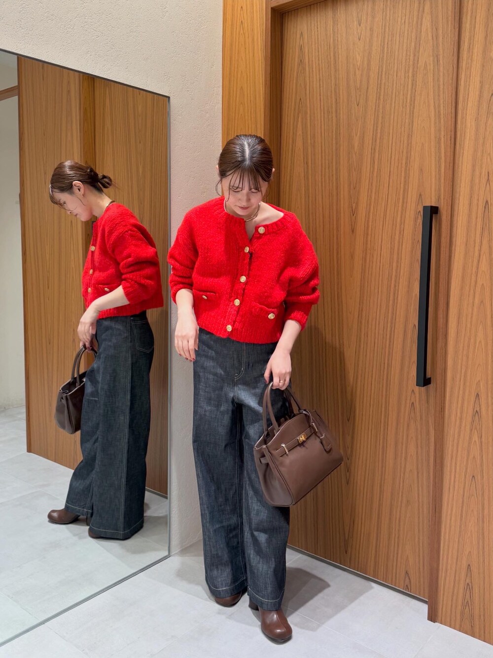 レッド系のニット/セーター、ブルー系のデニムパンツ、ブラウン系のブーツを着用したレディースの秋コーディネートの2枚目の写真