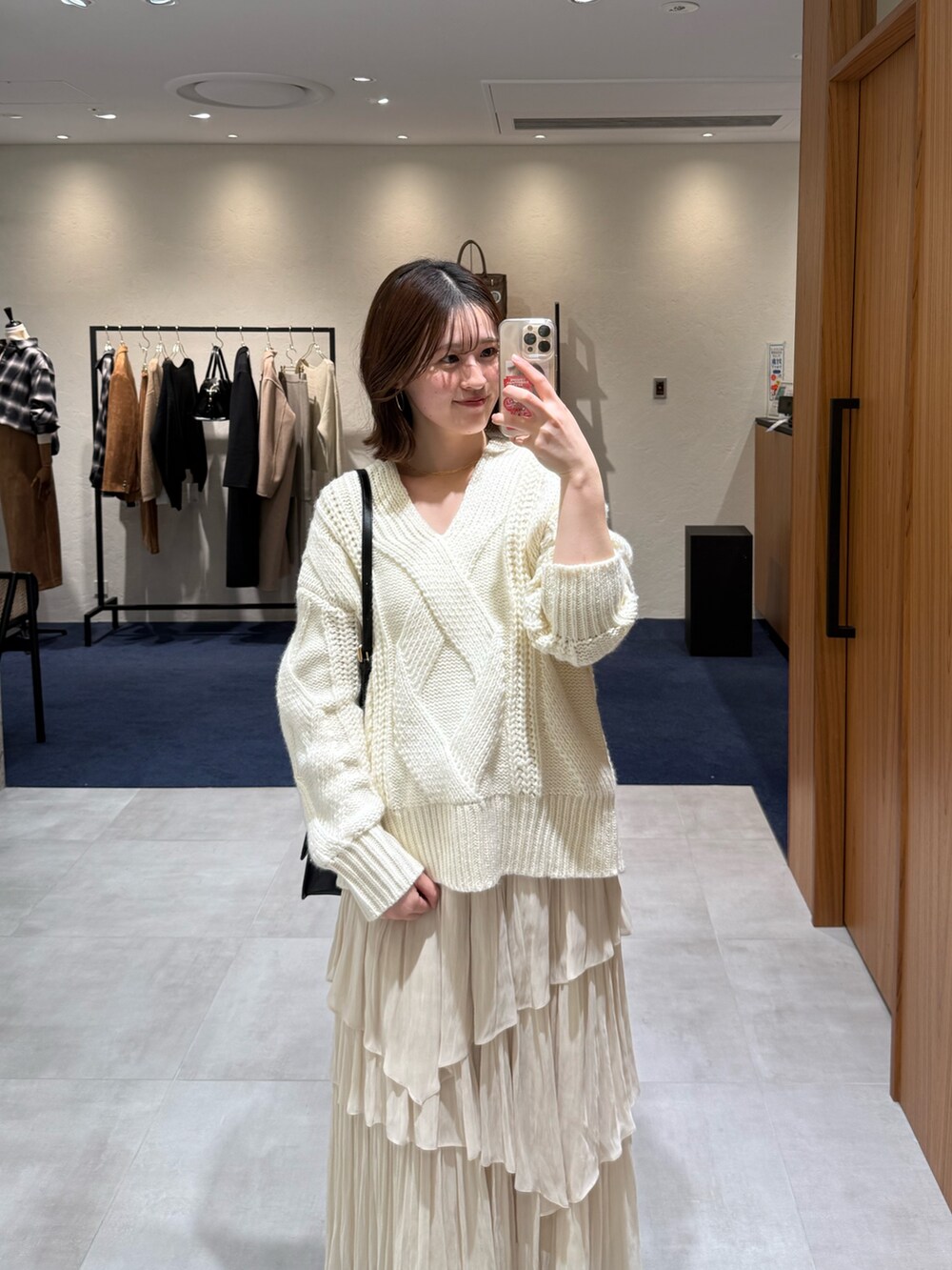 ホワイト系のニット/セーター、ホワイト系のスカート、ブラック系のブーツを着用したレディースの冬コーディネートの2枚目の写真