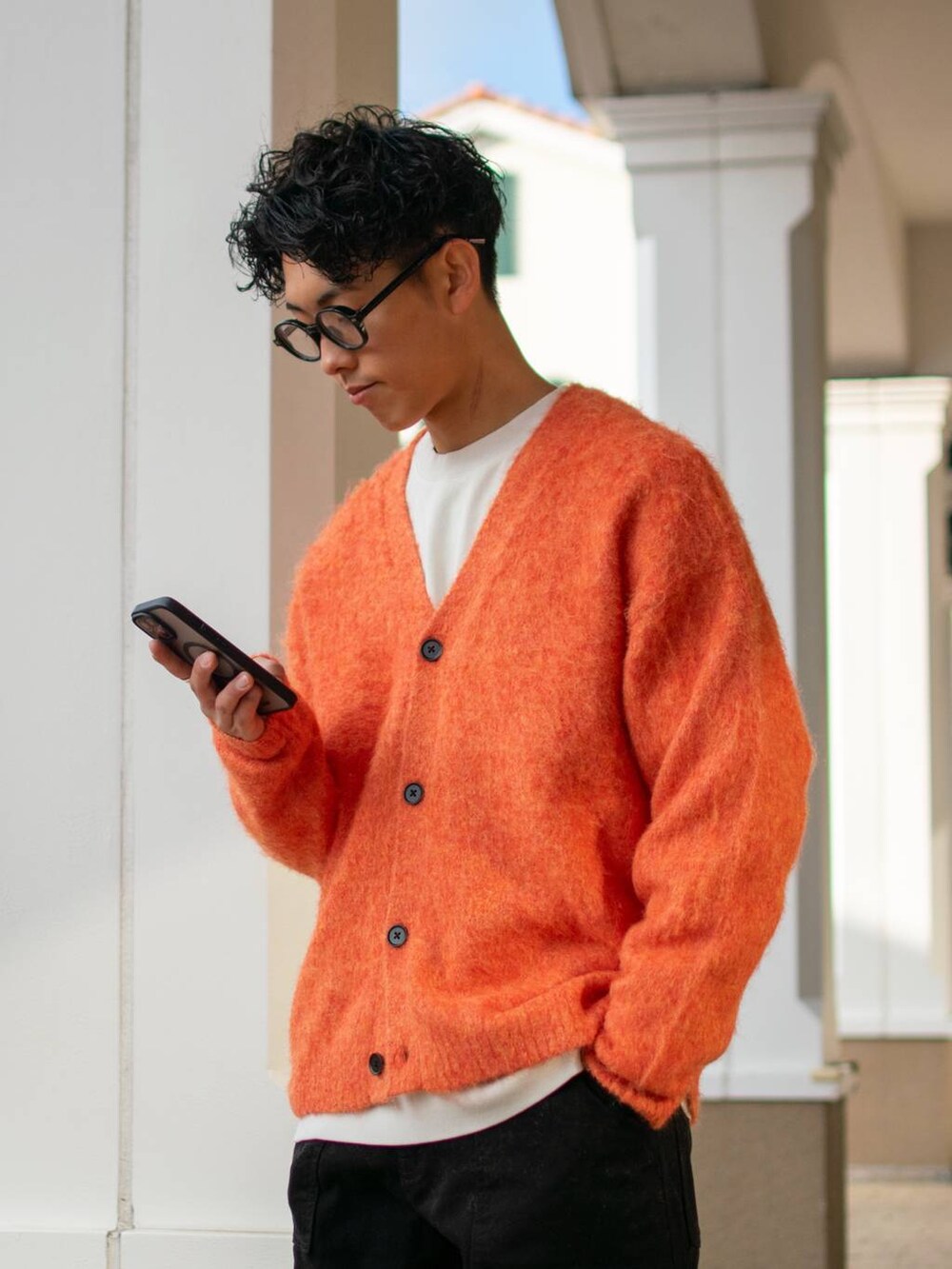 ブラック系のデニムパンツ、ホワイト系のスウェット、オレンジ系のカーディガン/ボレロを着用したメンズの冬コーディネートの5枚目の写真