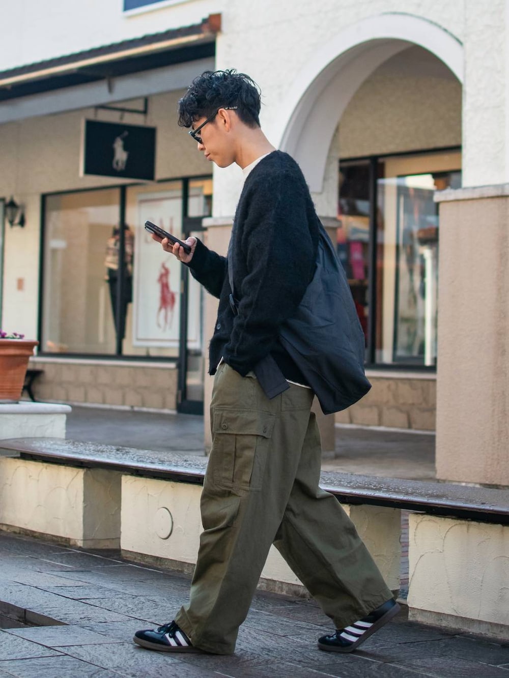 ブラック系のショルダーバッグ、グリーン系のカーゴパンツ、ホワイト系のスウェットを着用したメンズの冬コーディネートの2枚目の写真