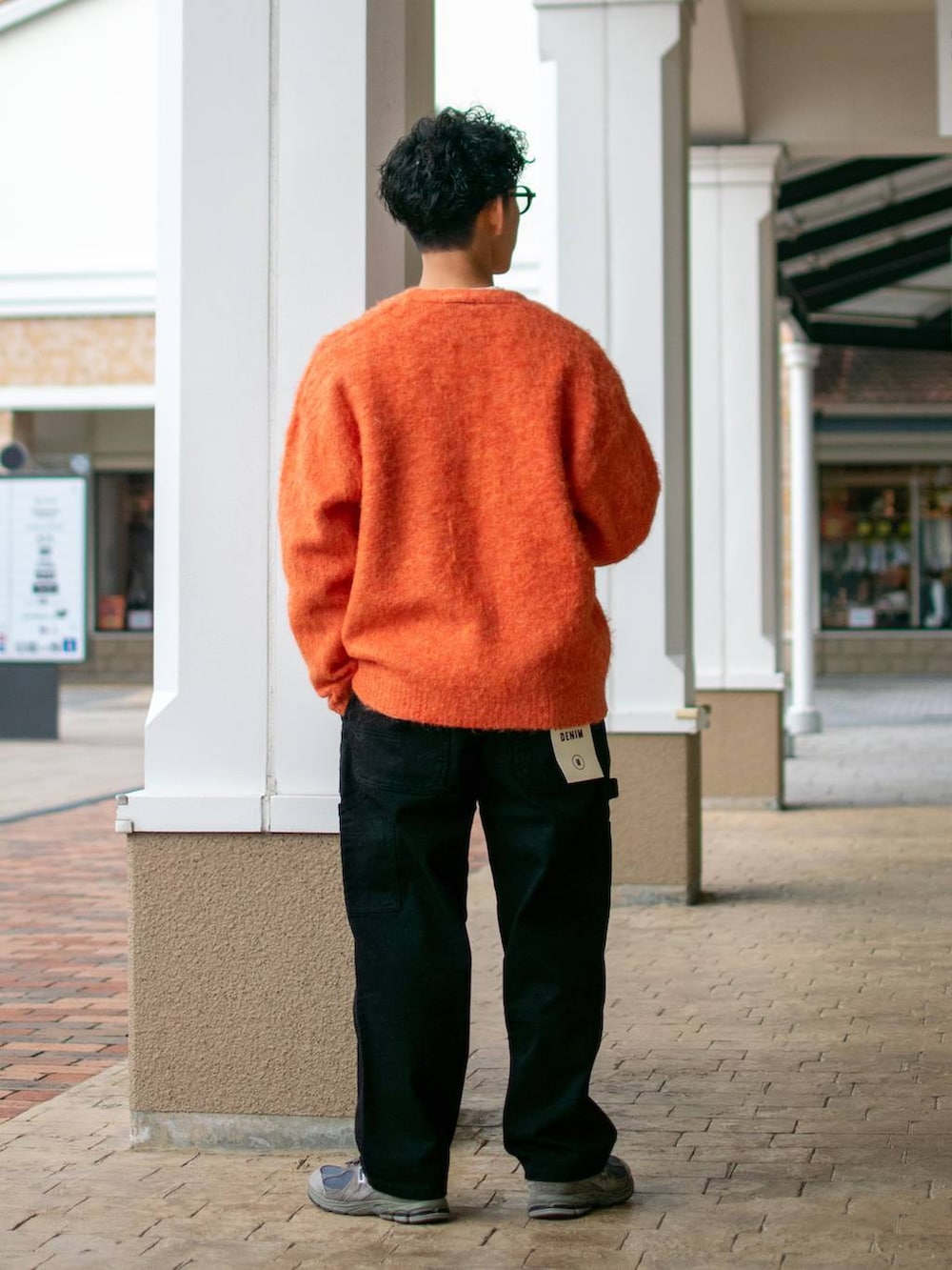 ブラック系のデニムパンツ、ホワイト系のスウェット、オレンジ系のカーディガン/ボレロを着用したメンズの冬コーディネートの4枚目の写真