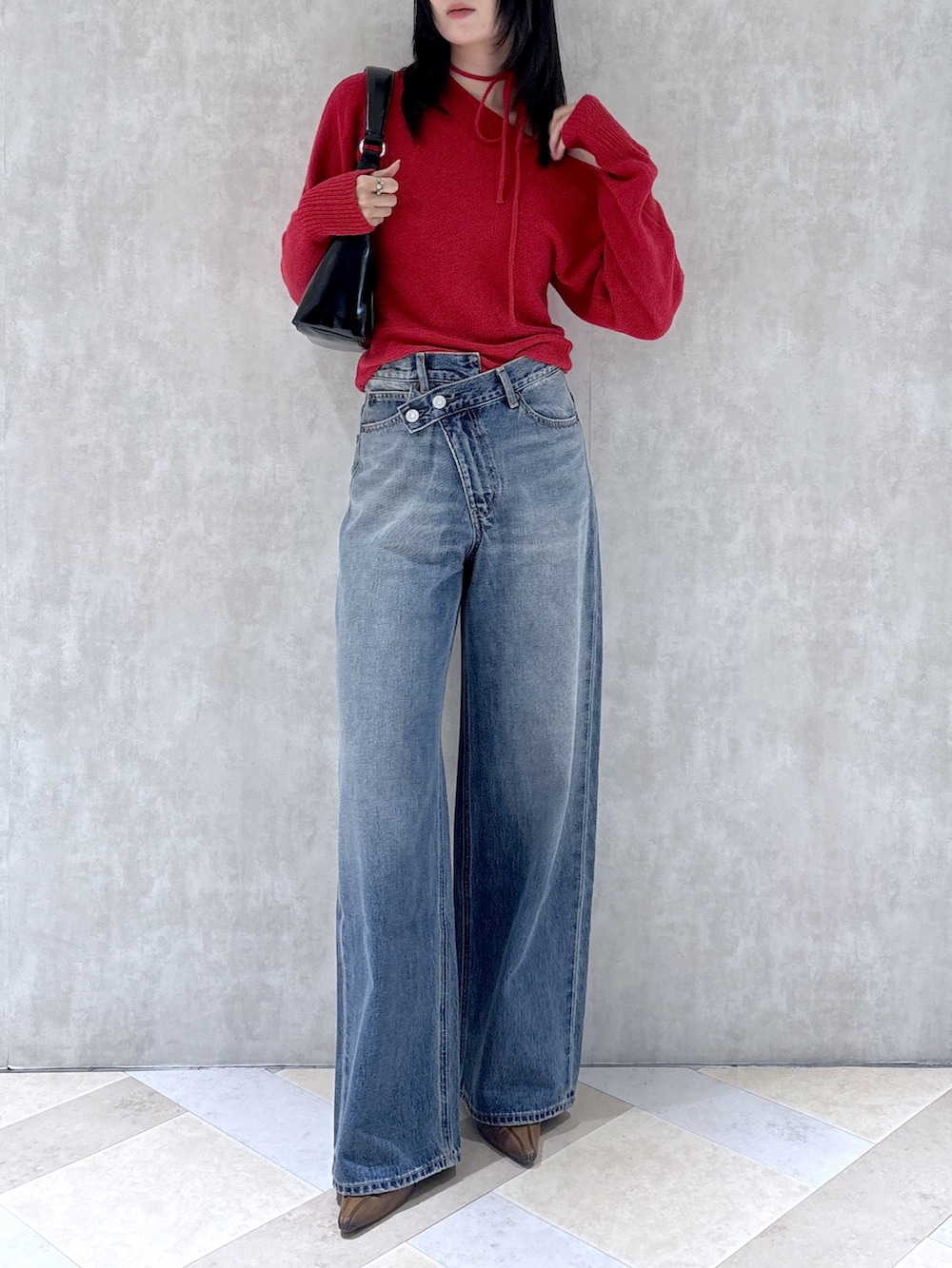 レッド系のニット/セーター、ブルー系のデニムパンツ、ブラウン系のパンプスを着用したレディースの秋コーディネートの5枚目の写真