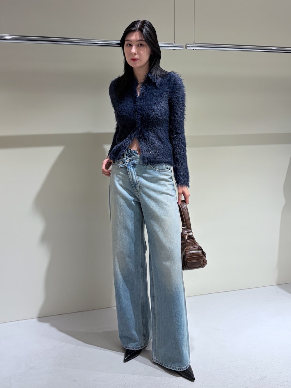 ブルー系のニット/セーター、ブルー系のデニムパンツ、ブラック系のブーツを着用したレディースの秋コーディネートの2枚目の写真