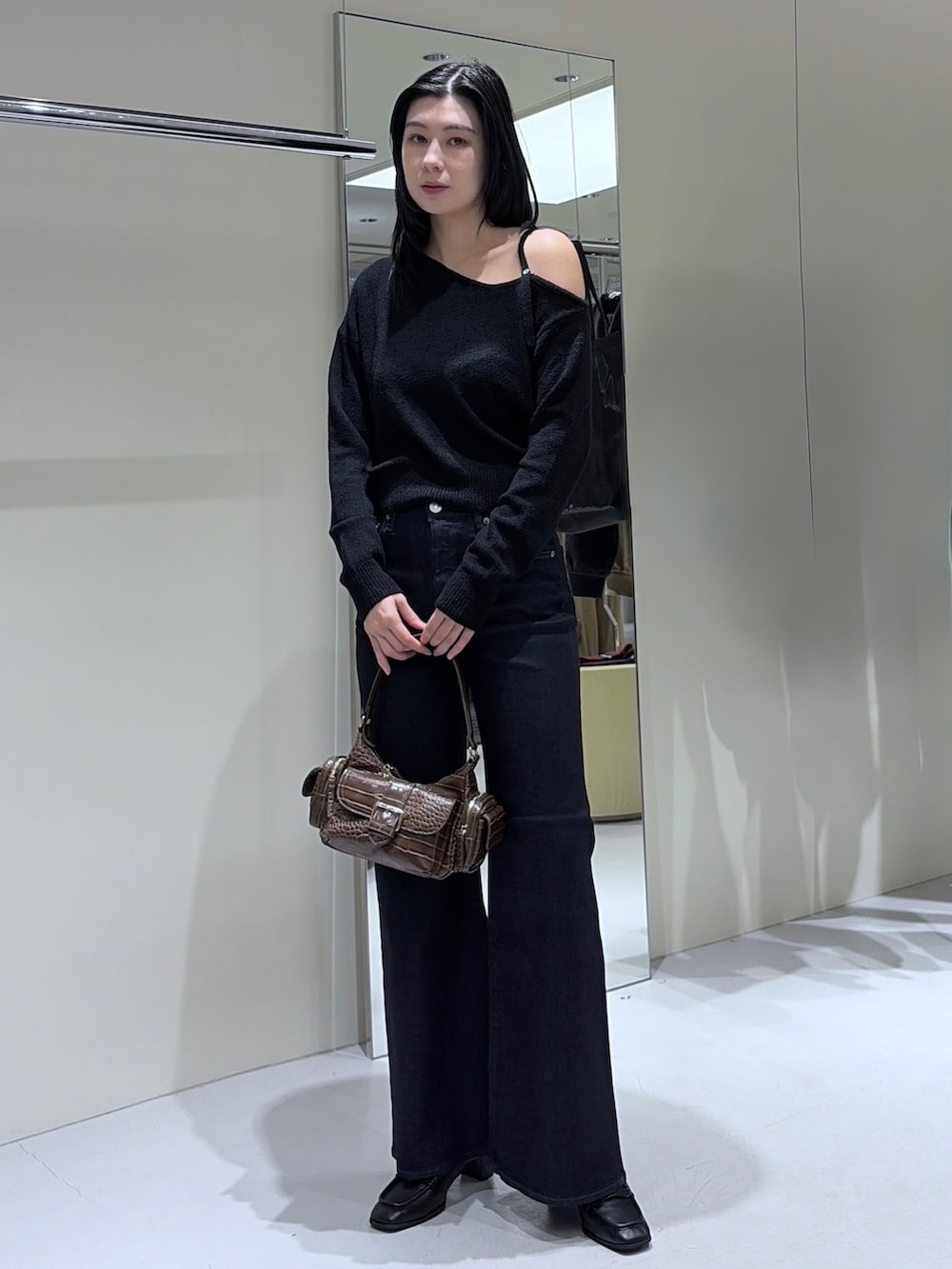 ブラック系のニット/セーター、ブラウン系のショルダーバッグ、ブルー系のデニムパンツを着用したレディースの秋コーディネートの3枚目の写真