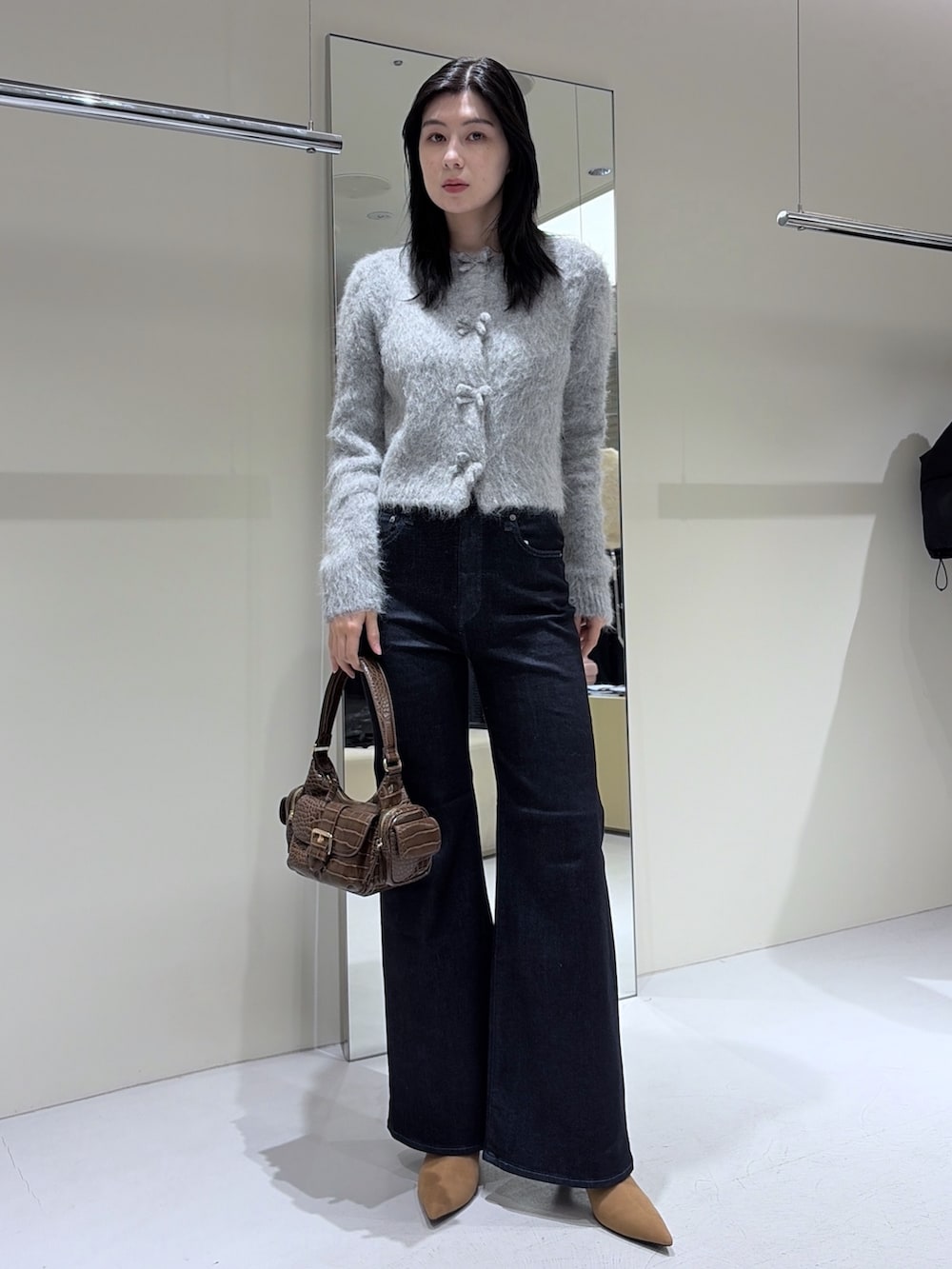 ベージュ系のブーツ、ブルー系のデニムパンツ、グレー系のカーディガン/ボレロを着用したレディースの冬コーディネートの2枚目の写真