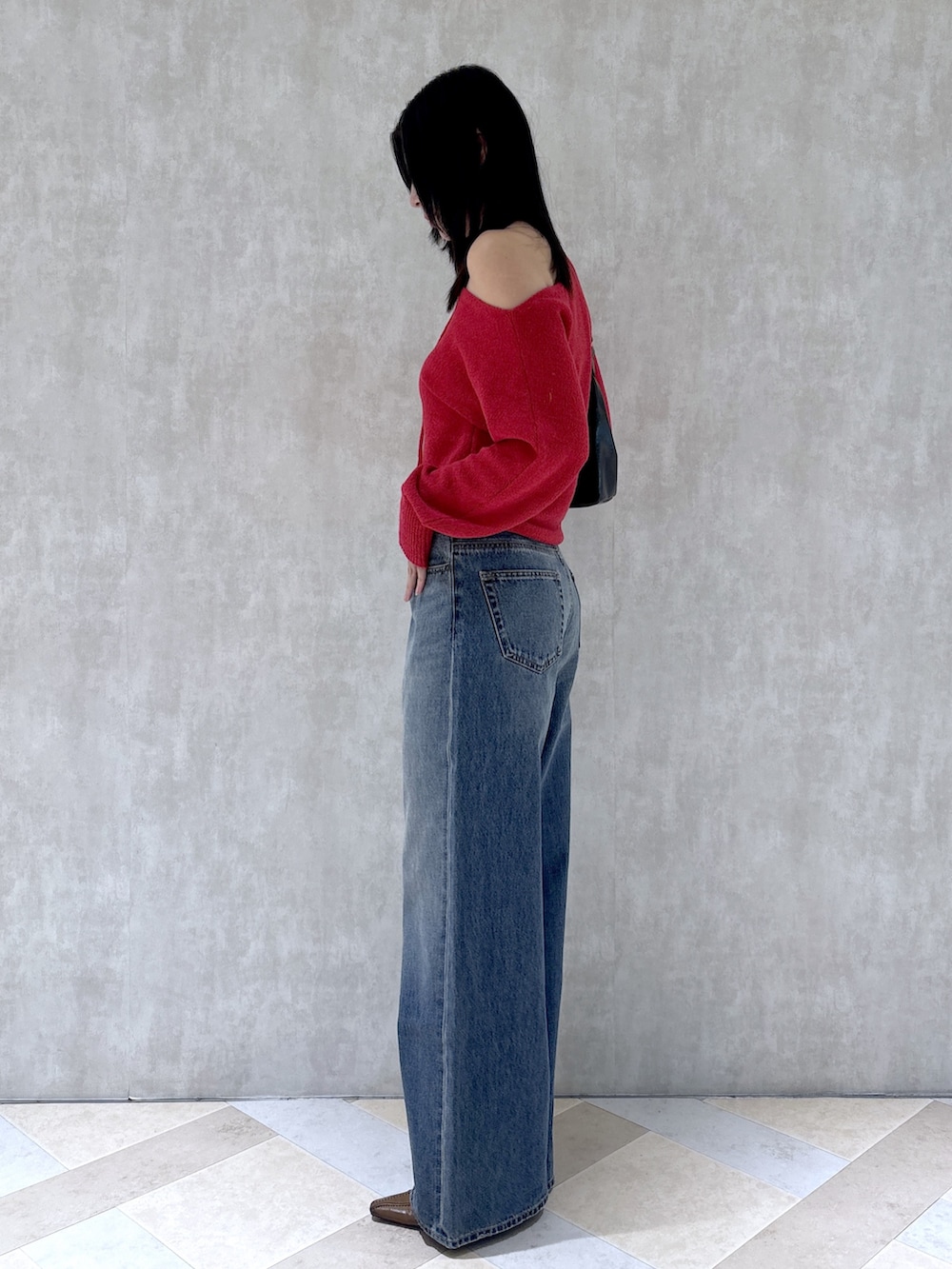 レッド系のニット/セーター、ブルー系のデニムパンツ、ブラウン系のパンプスを着用したレディースの秋コーディネートの3枚目の写真