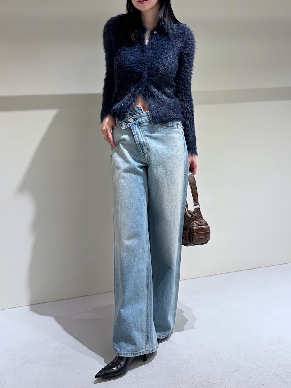 ブルー系のニット/セーター、ブルー系のデニムパンツ、ブラック系のブーツを着用したレディースの秋コーディネートの4枚目の写真