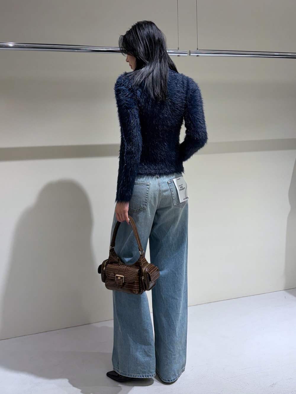 ブルー系のニット/セーター、ブルー系のデニムパンツ、ブラック系のブーツを着用したレディースの秋コーディネートの3枚目の写真