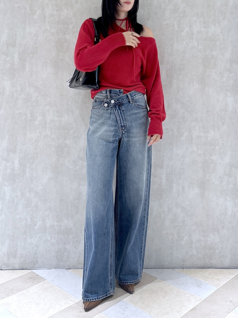 レッド系のニット/セーター、ブルー系のデニムパンツ、ブラウン系のパンプスを着用したレディースの秋コーディネートの2枚目の写真