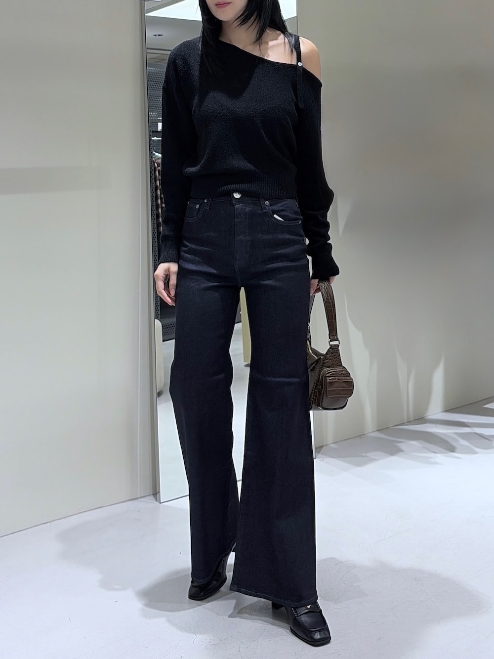 ブラック系のニット/セーター、ブラウン系のショルダーバッグ、ブルー系のデニムパンツを着用したレディースの秋コーディネートの2枚目の写真