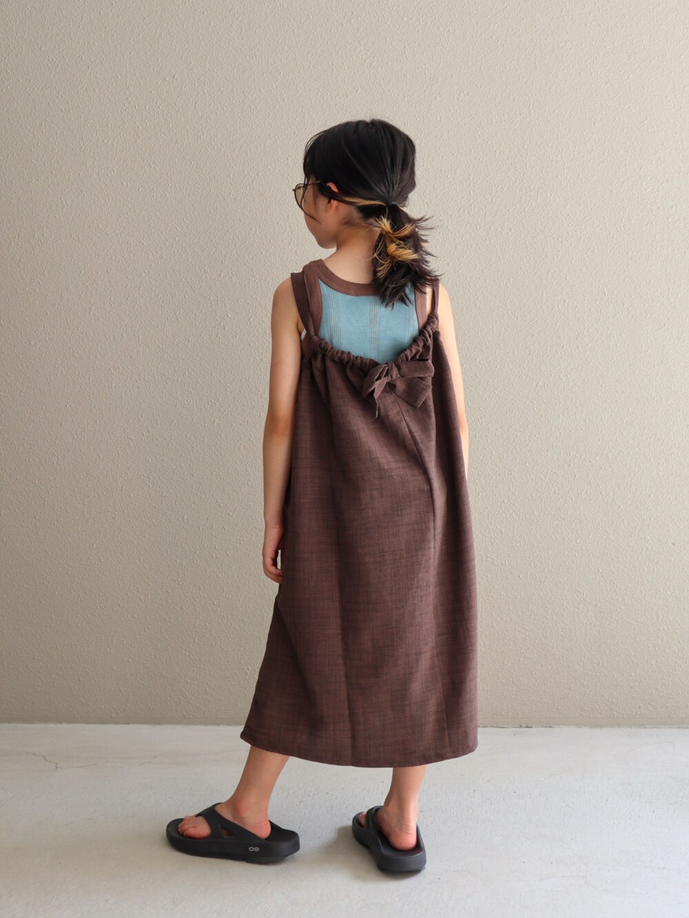 ブラウン系のワンピース、ブラック系のサンダル、ブルー系のタンクトップを着用したキッズの夏コーディネートの5枚目の写真