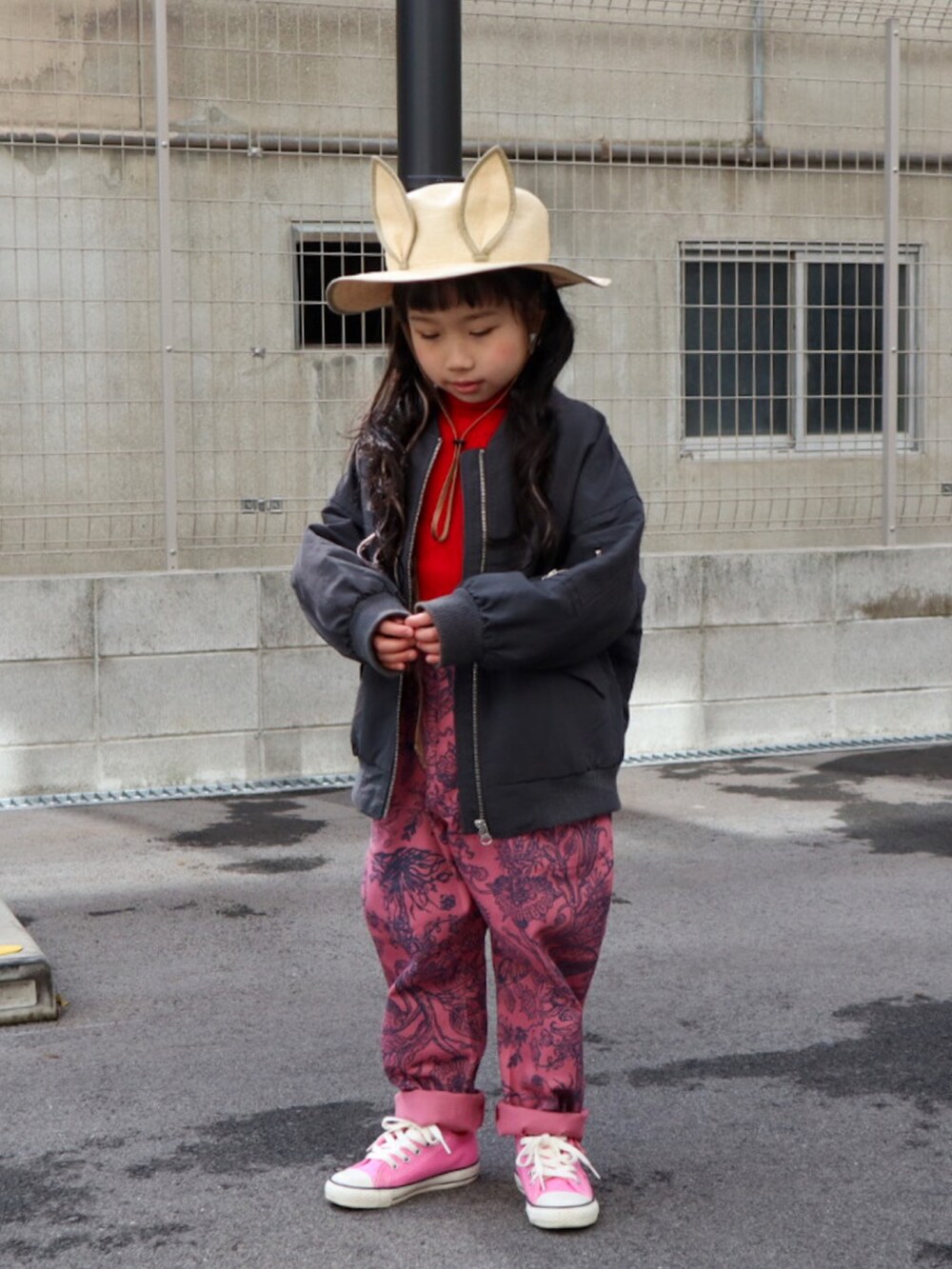 グレー系のMA-1、レッド系のニット/セーター、ピンク系のパンツを着用したキッズの冬コーディネートの2枚目の写真