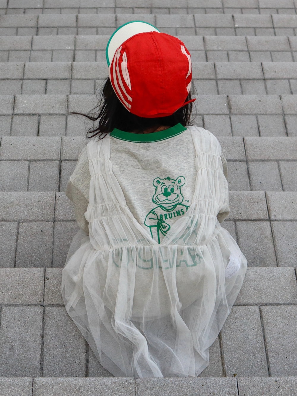 ホワイト系のチュニック、グリーン系のTシャツ/カットソー、ホワイト系のデニムパンツを着用したキッズの春コーディネートの3枚目の写真