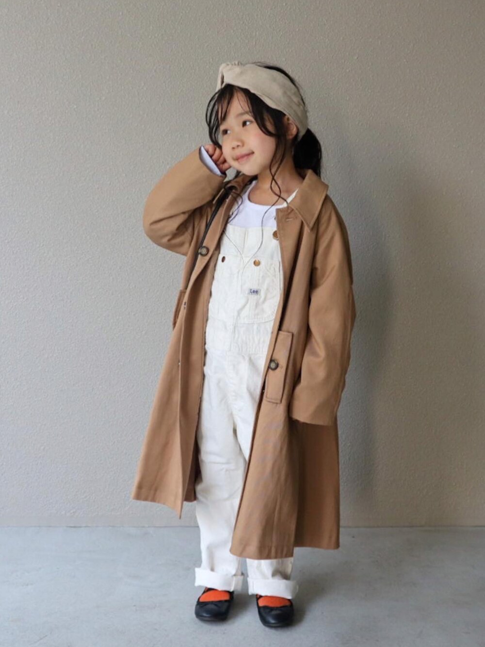 ベージュ系のステンカラーコート、ブルー系のTシャツ/カットソー、ホワイト系のサロペット/オーバーオールを着用したキッズの春コーディネートの2枚目の写真