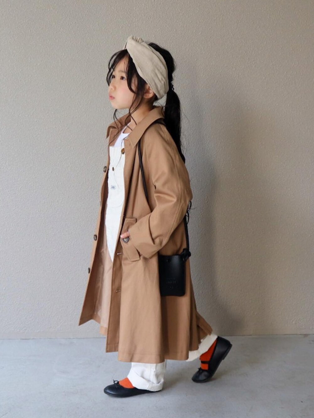 ベージュ系のステンカラーコート、ブルー系のTシャツ/カットソー、ホワイト系のサロペット/オーバーオールを着用したキッズの春コーディネートの3枚目の写真