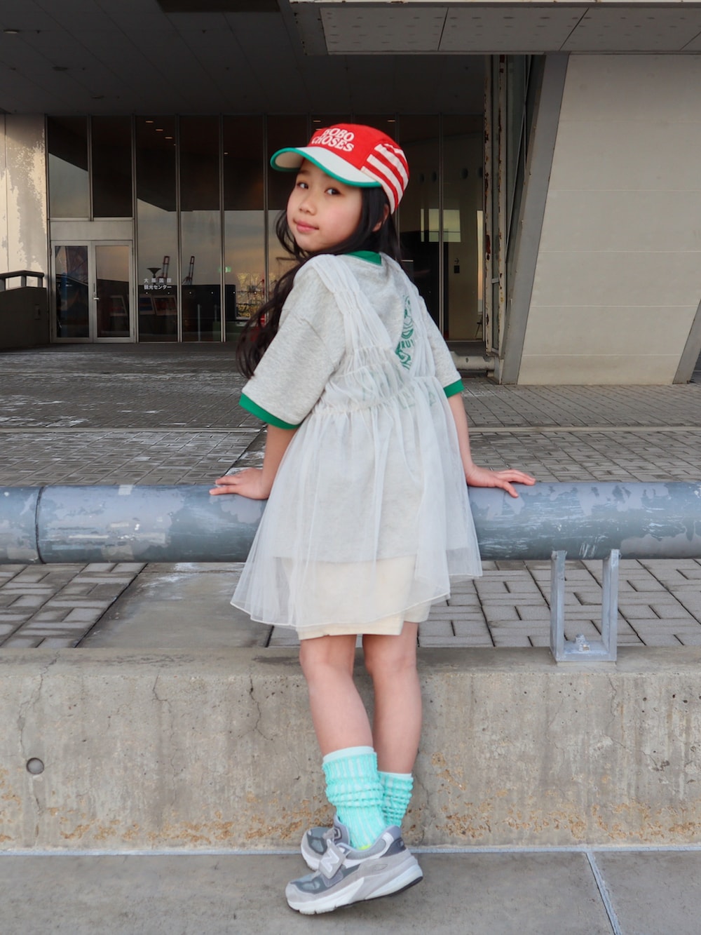 ホワイト系のチュニック、グリーン系のTシャツ/カットソー、ホワイト系のデニムパンツを着用したキッズの春コーディネートの5枚目の写真