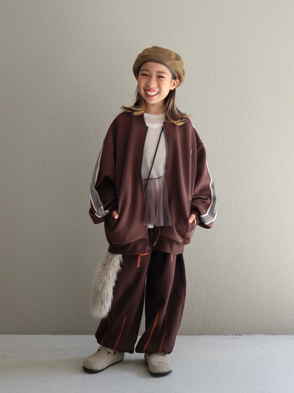 ブラウン系のジャケット/アウター、ブラウン系のパンツ、ベージュ系のサンダルを着用したキッズの秋コーディネートの2枚目の写真