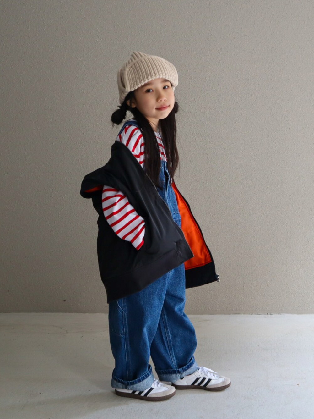 レッド系のTシャツ/カットソー、ブルー系のサロペット/オーバーオール、ブラック系のMA-1を着用したキッズの冬コーディネートの2枚目の写真