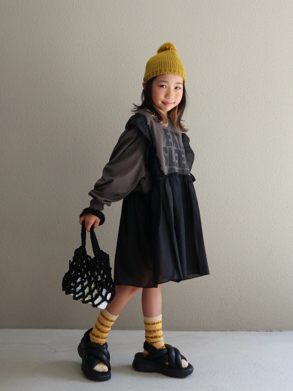 ブラック系のスカート、グレー系のワンピース、ブラック系のサンダルを着用したキッズの秋コーディネートの4枚目の写真
