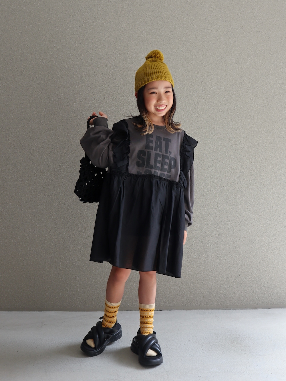 ブラック系のスカート、グレー系のワンピース、ブラック系のサンダルを着用したキッズの秋コーディネートの3枚目の写真